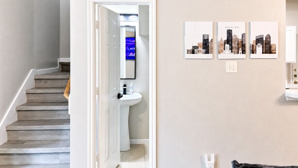 A staircase leading to a bathroom with a sink and a mirror. - Space City 4BR - 7 Min to NRG Stadium (Houston)