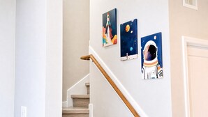 A staircase with a wooden handrail and a wall with three space-themed paintings. - Space City 4BR - 7 Min to NRG Stadium (Houston)