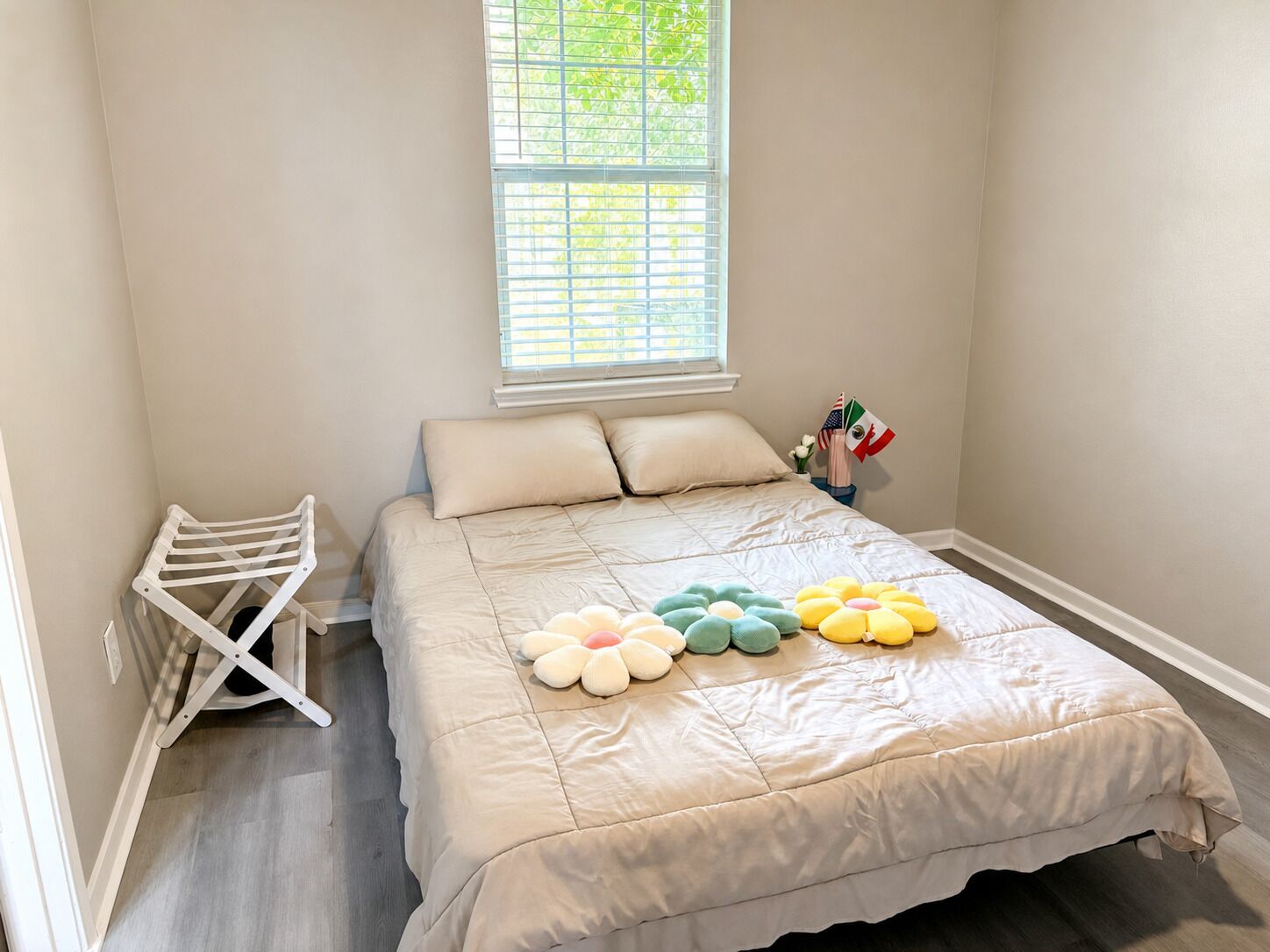 Una camera da letto con un letto, una finestra, uno stendibiancheria e un tavolino con delle bandiere.