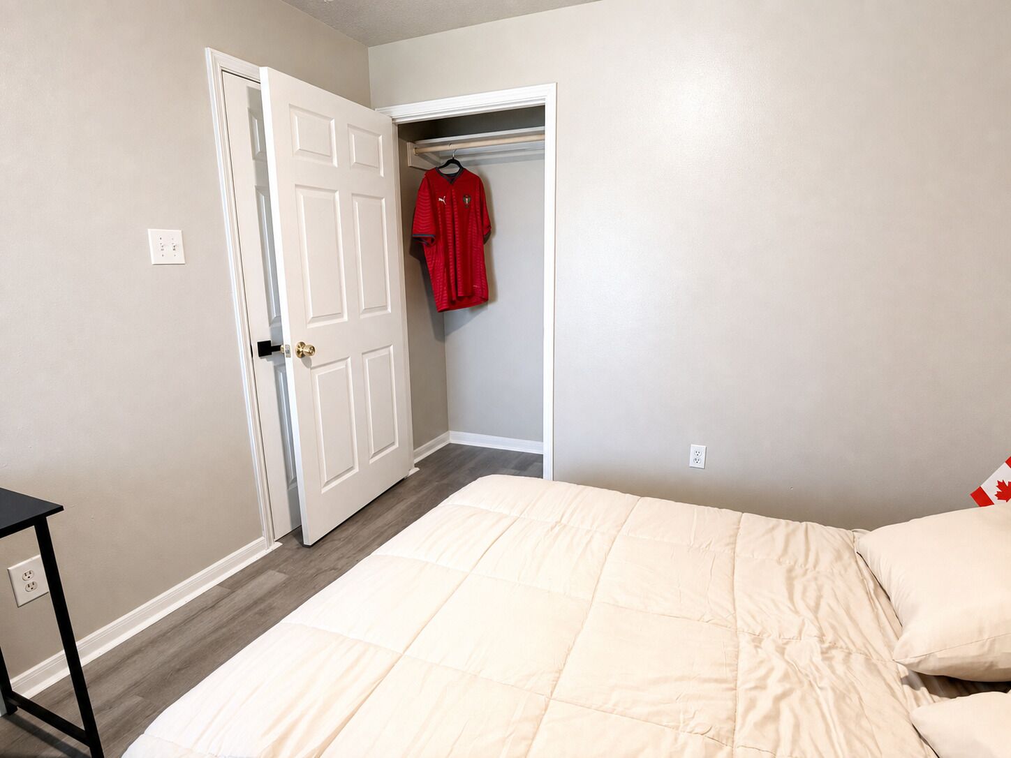Un dormitorio con cama, un armario con una prenda roja y una puerta.