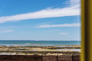 Un paysage côtier avec une clôture en bois au premier plan et un ciel dégagé.