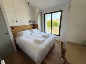 Ein Schlafzimmer mit einem hölzernen Bett, einem Fenster mit Blick auf Grünflächen und einem Holzboden.