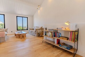 A spacious living area with a wooden floor, a sofa, a coffee table, and a bookshelf filled with books. - Le Vieil · Renovated house · Beach & sea view (Noirmoutier-en-l'Île)
