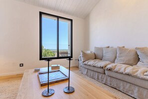 Un salon moderne avec une grande fenêtre, une table basse en bois et un canapé beige.