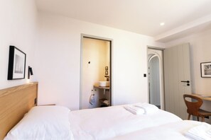 A hotel room with a bed, a desk, and a bathroom visible through an open door. - Le Vieil · Renovated house · Beach & sea view (Noirmoutier-en-l'Île)