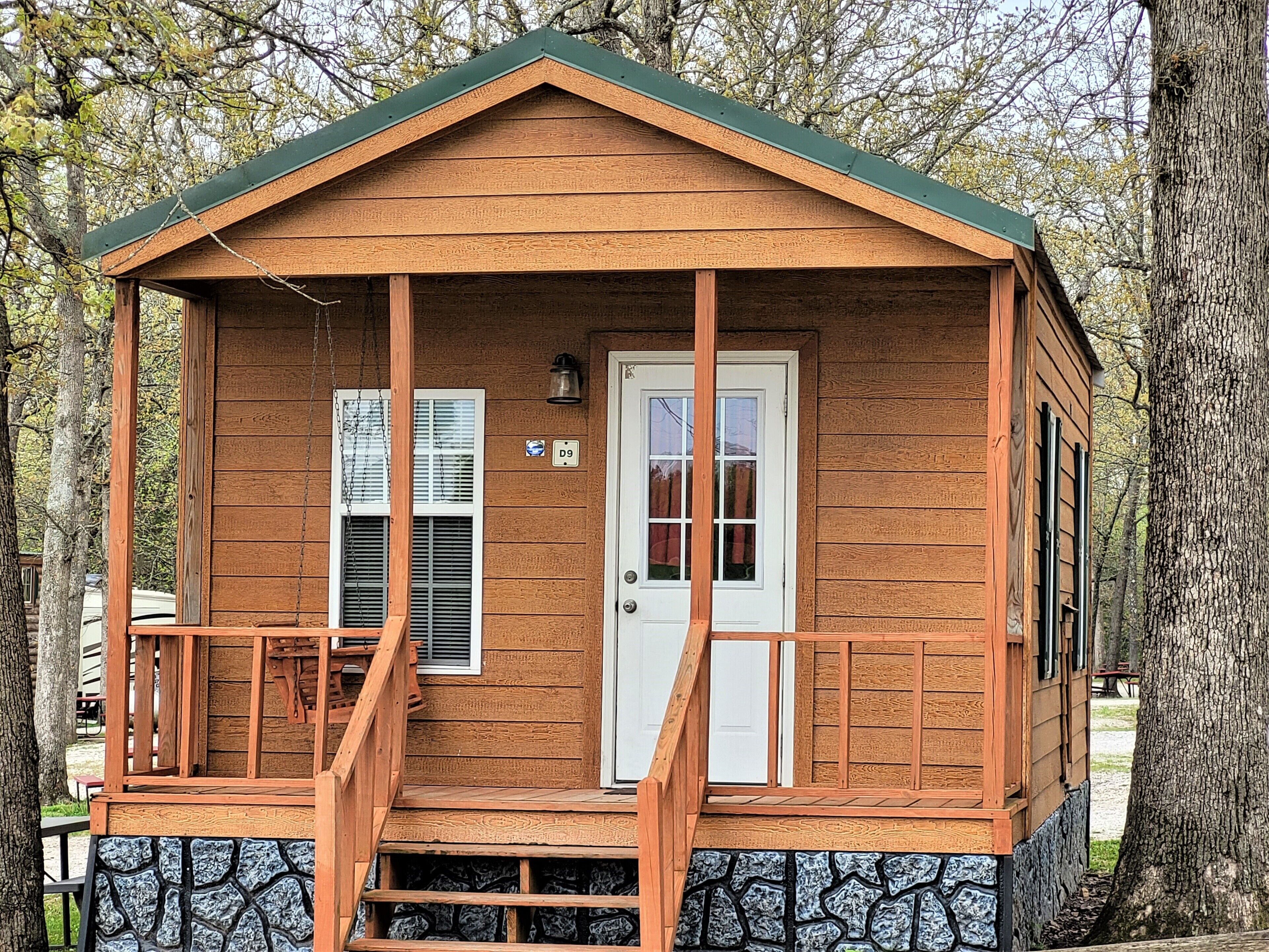A small wooden cabin with a porch, a door, and a window.