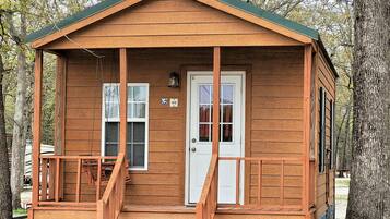 A small wooden cabin with a porch, a door, and a window.