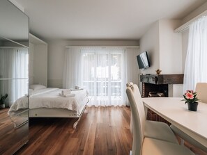 Ein modernes Hotelzimmer mit Bett, Schreibtisch, Sessel, Fernseher und Kamin.