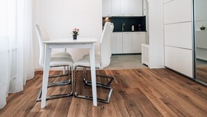 A modern kitchen with white cabinets, a dining table with chairs, and a small potted plant. - Laret 6-11 by Interhome (Laax)