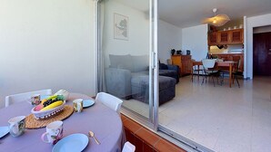 Ein Essbereich mit einem Tisch für zwei Personen, einer Couch und einer Küche im Hintergrund.