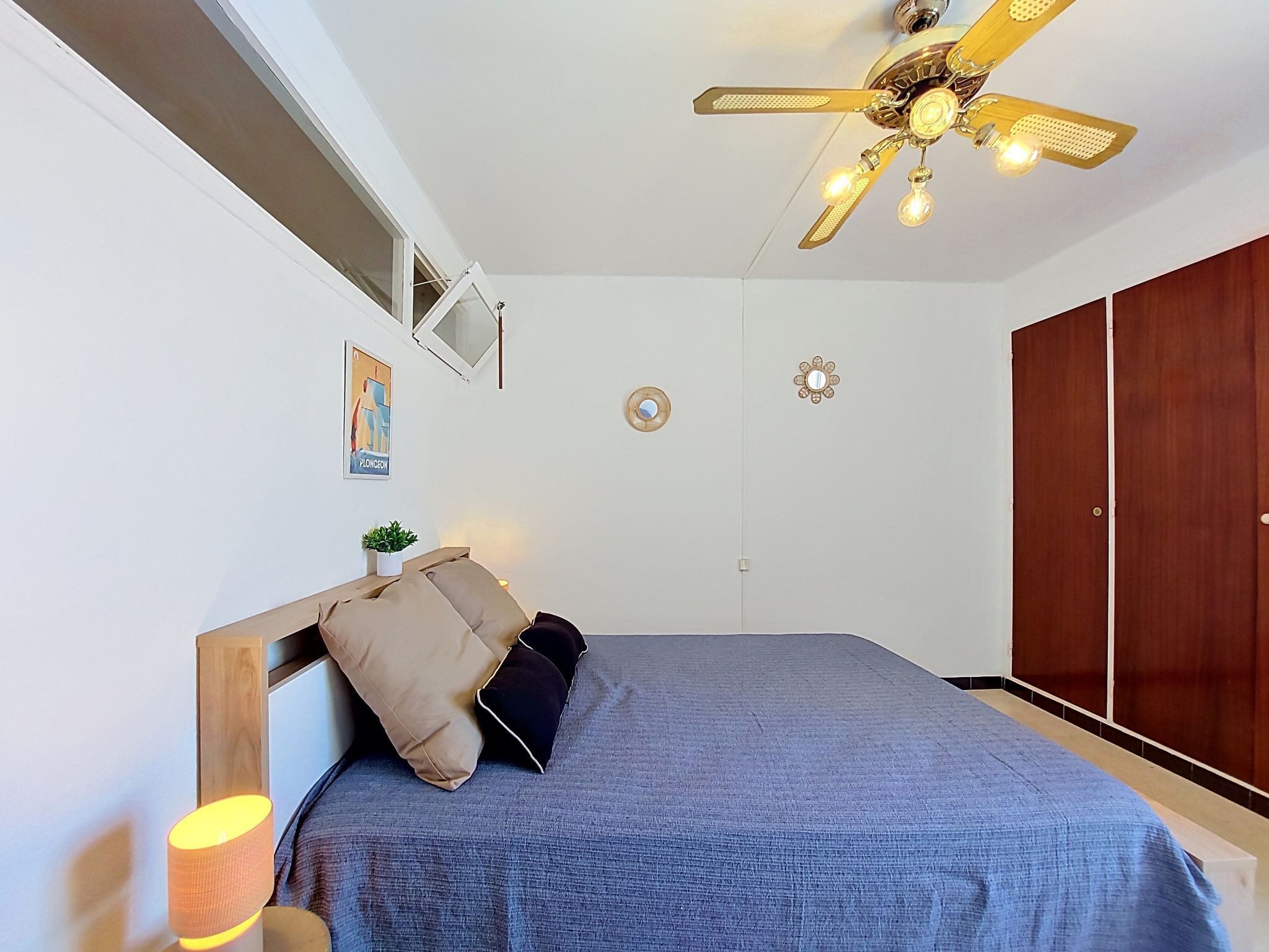 Ein Schlafzimmer mit Bett, Deckenventilator, Wand-Fernseher und Kleiderschrank.