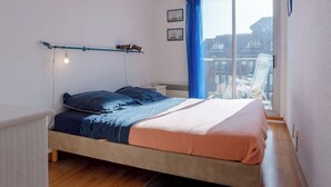 Un dormitorio con cama, ventana con vista y ventilador de techo.