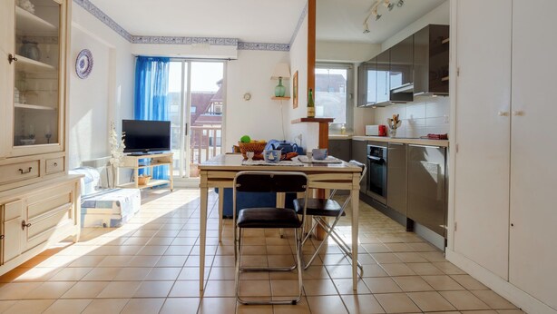 Una cocina moderna con una mesa de comedor, sillas y un televisor.