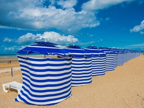 Eine Reihe von gestreiften Strandsonnenschirmen am sandigen Strand.