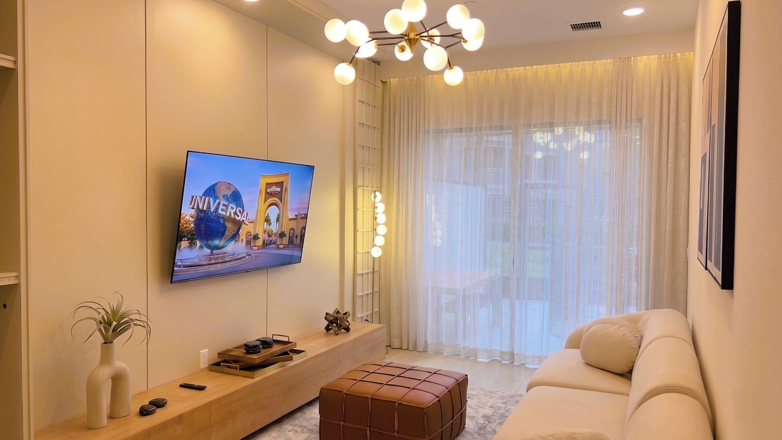 A living room with a TV mounted on the wall, a sofa, a coffee table, and a decorative floor lamp.