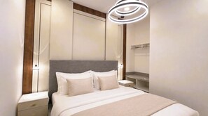 Une chambre d’hôtel moderne dotée d’un grand lit, de tables de chevet, d’une banquette intégrée et d’un miroir fixé au mur.