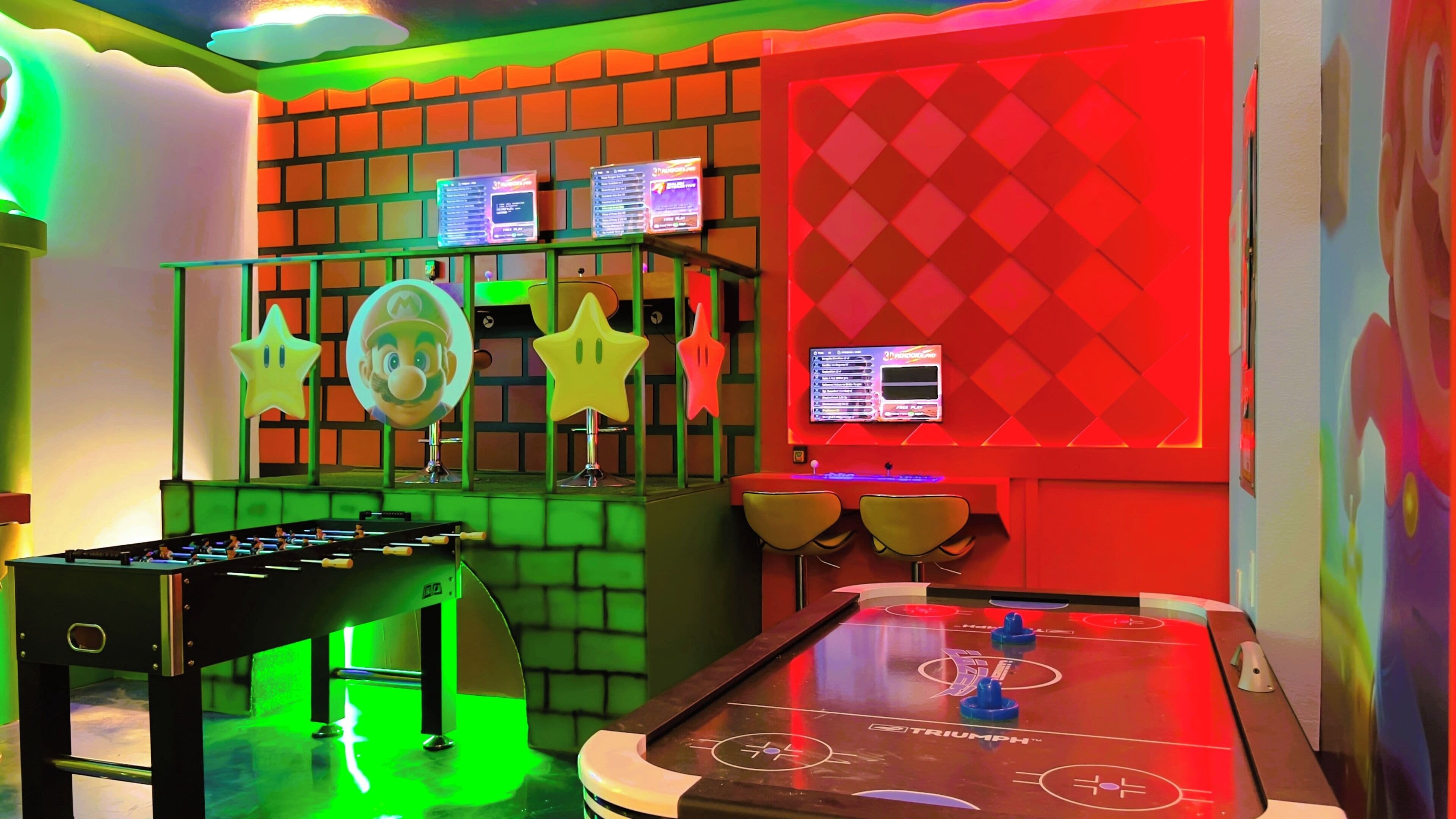 A room with a foosball table, a table tennis table, and a wall with a diamond pattern.