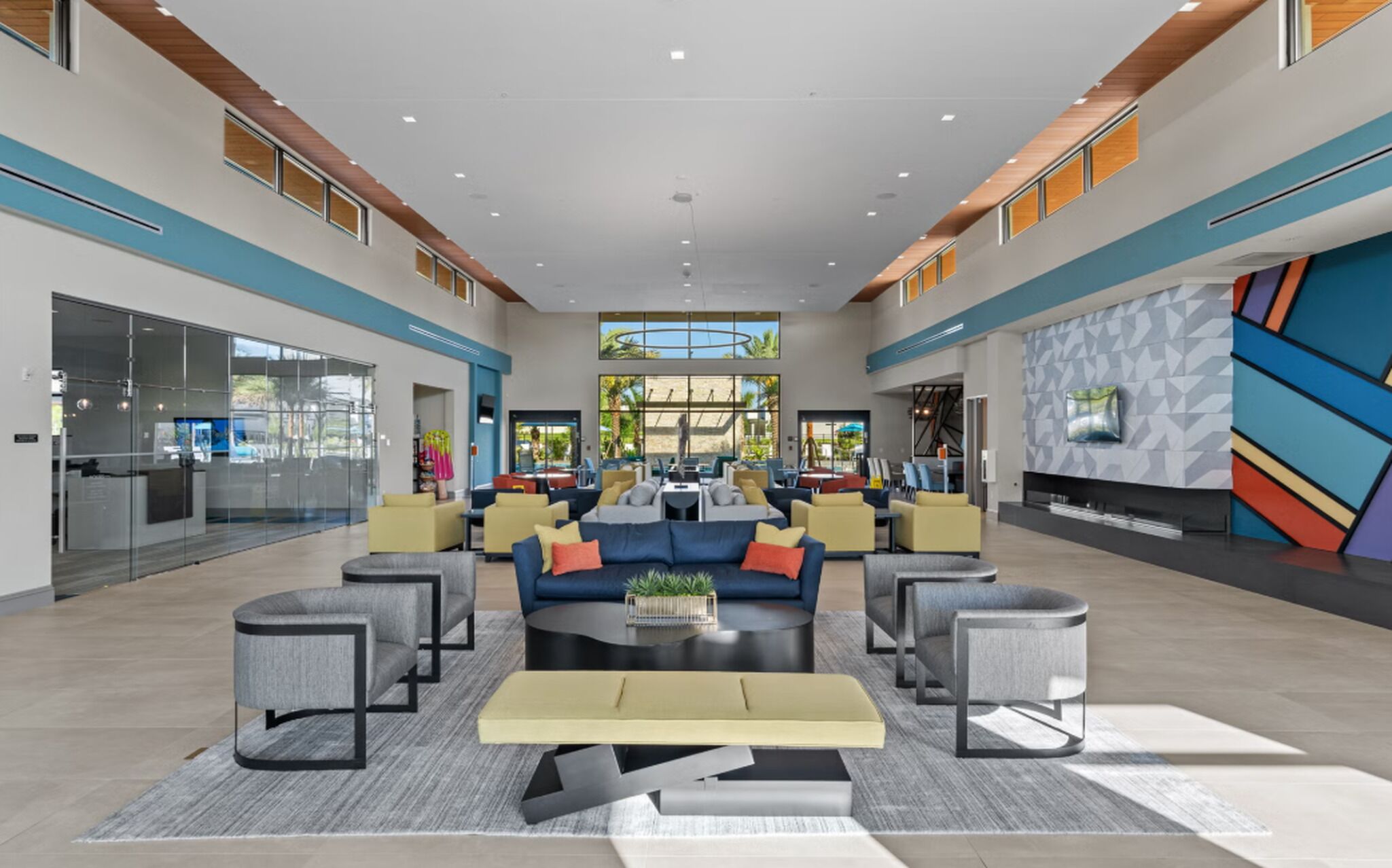 A spacious lobby with a central seating area, large windows, and a modern geometric wall design.