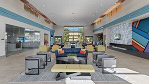 A spacious lobby with a central seating area, large windows, and a modern geometric wall design. - Luxury 5BR/5BA - Villa at Paradiso Grande Near Universal, Sea World and more (Orlando)
