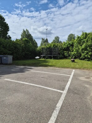 Un parking avec des places délimitées, un trampoline et une poubelle.