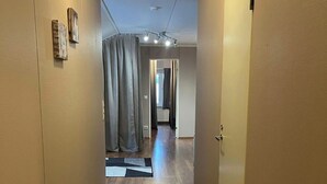 Ein Korridor mit Holzböden, einem schwarzen Teppich und einer Tür rechts.