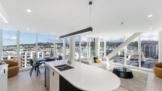 Un apartamento moderno con cocina, comedor y sala de estar, con amplios ventanales que ofrecen vistas a la ciudad.
