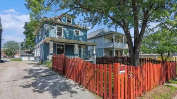 A residential street with houses, a red fence, and trees. - Midtown-2 King Beds•Near Streetcar•30+Nights-WIFI (kansas city)