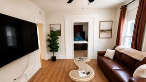 A living room with a flat-screen TV, a brown leather sofa, a coffee table, and a potted plant. - Midtown-2 King Beds•Near Streetcar•30+Nights-WIFI (kansas city)