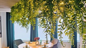 Uma área de refeições com uma mesa redonda, quatro cadeiras e uma planta pendurada acima.