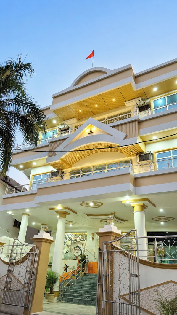 A multi-story hotel with a prominent red flag on top, a central atrium with a staircase, and balconies on each floor.