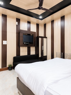 A modern bedroom with a bed, a TV mounted on the wall, a ceiling fan, and a wardrobe.