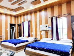 A hotel room with two beds, wooden paneling, a ceiling fan, an air conditioning unit, and a window with curtains. - Hotel Shree Inn Uttarakhand (Sitarganj)