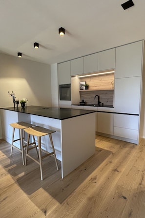 Eine moderne Küche mit einer zentralen Kochinsel, Holzbarhocker und integrierten Geräten.