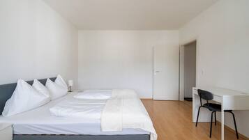 A bedroom with a bed, bedside table, chair, desk, and wardrobe.