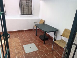 A small patio area with a table and two chairs, a window with decorative bars, and a tiled floor. - Apartment 300 meters from the beach and the marina (Aguadulce)