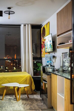 A compact bedroom with a bed, a small table, and a window with curtains. - Enjoy a soothing stay in a modern apartment in Nairobi. (Nairobi)