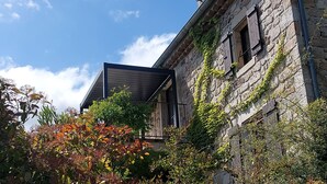 Ein aus Stein gebautes Gebäude mit Efeu, einem hölzernen Balkon und blauem Himmel.