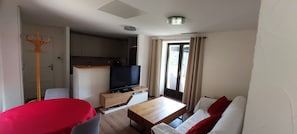 A compact living space with a kitchenette, a television, a dining table, and a sofa. - Gîte de Laulagne : Nature, Calm and Comfort. Independent apartment. (Saint-André-Lachamp)