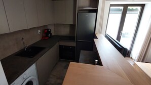 Eine kompakte Küche mit Waschmaschine, Kaffeemaschine und Kühlschrank.