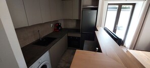 A compact kitchen with a washing machine, a coffee maker, and a refrigerator. - Gîte de Laulagne : Nature, Calm and Comfort. Independent apartment. (Saint-André-Lachamp)