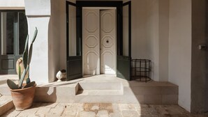 A clean entrance with a white door, a potted plant, and a metal stand. - Large charming house in Puglia, not far from the Ionian Sea. (Nardò)
