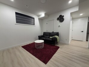 Ein modernes Wohnzimmer mit einem schwarzen Ledersofa, einem roten Teppich und einem weißen runden Tisch.