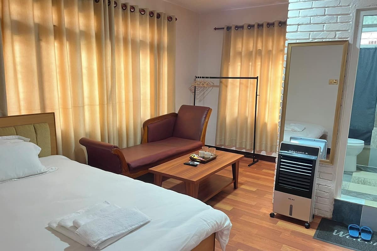 Une chambre dâhĂŽtel comprenant un lit, un canapĂ©, une table basse, un bureau, un miroir, une armoire et une vue sur lâextĂ©rieur.