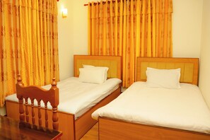 A hotel room with two single beds, wooden headboards, and a wooden chair. - The Nestle Cozy Homestay (Kathmandu)