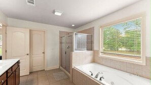 Un baño moderno con bañera, ducha y ventana con persianas.