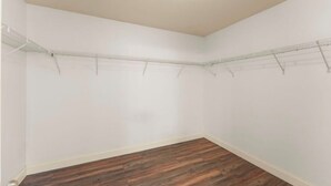 Una habitación con paredes blancas, suelo de madera y estanterías metálicas.