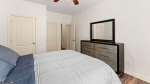 Un dormitorio con cama, cómoda, ventilador de techo y tres puertas.