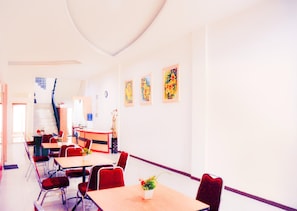 Une chambre d’hôtel avec un coin repas, un escalier et des œuvres d’art accrochées aux murs.