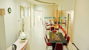 A conference room with a long table, red chairs, framed pictures on the walls, and a view through a glass door. - Cozy Twin Escape With Free Wifi and Parking (Bukittinggi)