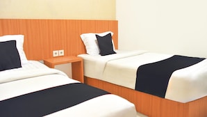 Two single beds with wooden headboards, white bedding, and black throw pillows in a hotel room. - Cozy Twin Escape With Free Wifi and Parking (Bukittinggi)